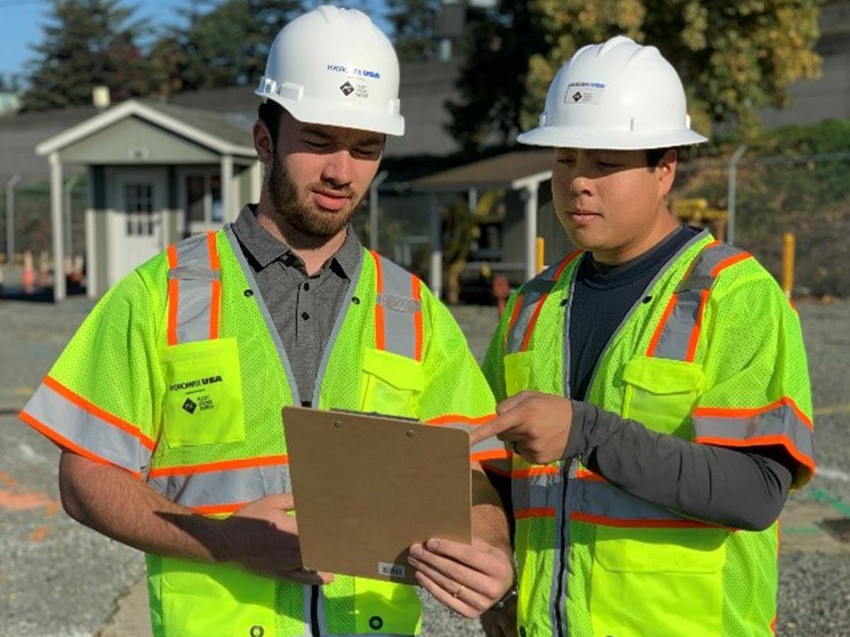 Two Hydromax USA workers consult a clipboard together.