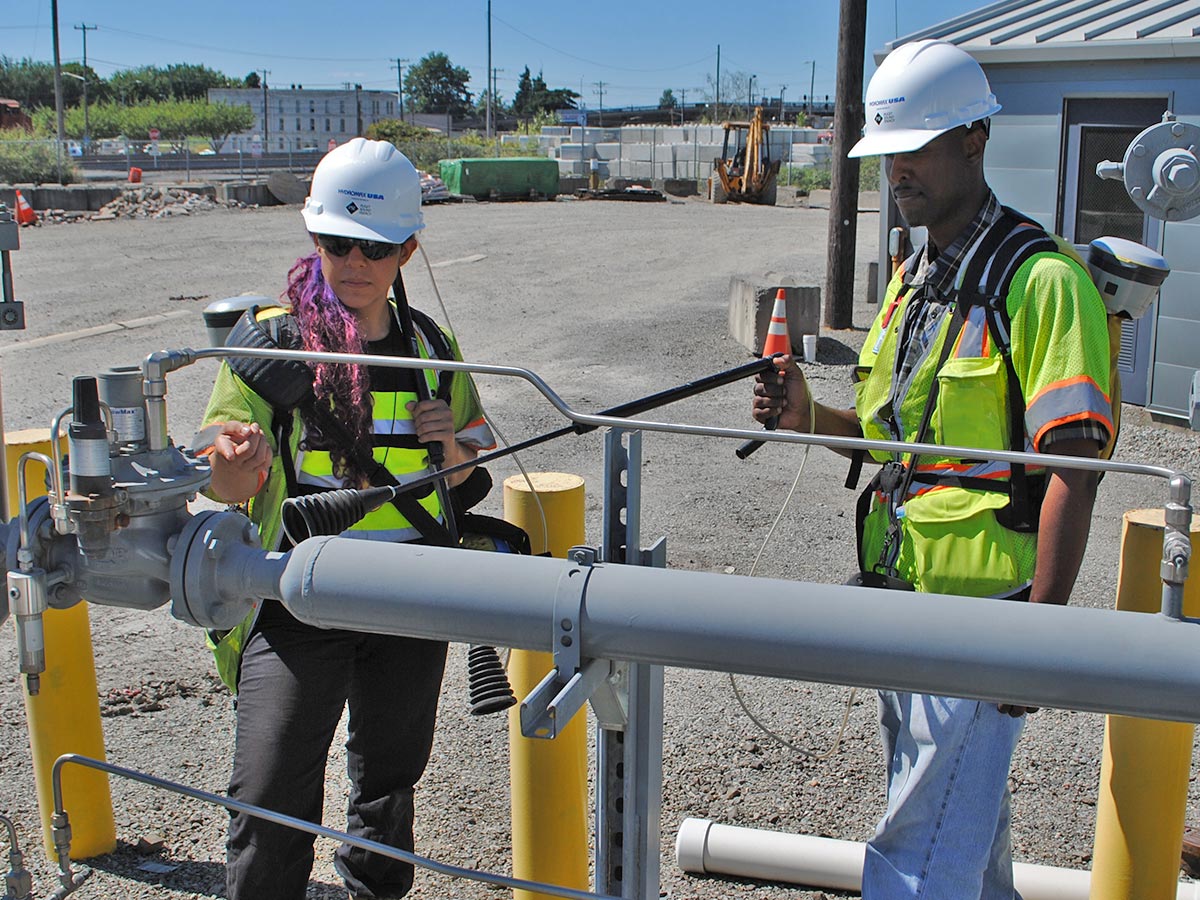 Two Hydromax USA workers check a gas valve with a sensor.
