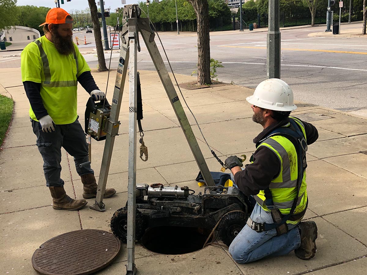 Two HydroMax USA workers working on a manhole during an inspection.