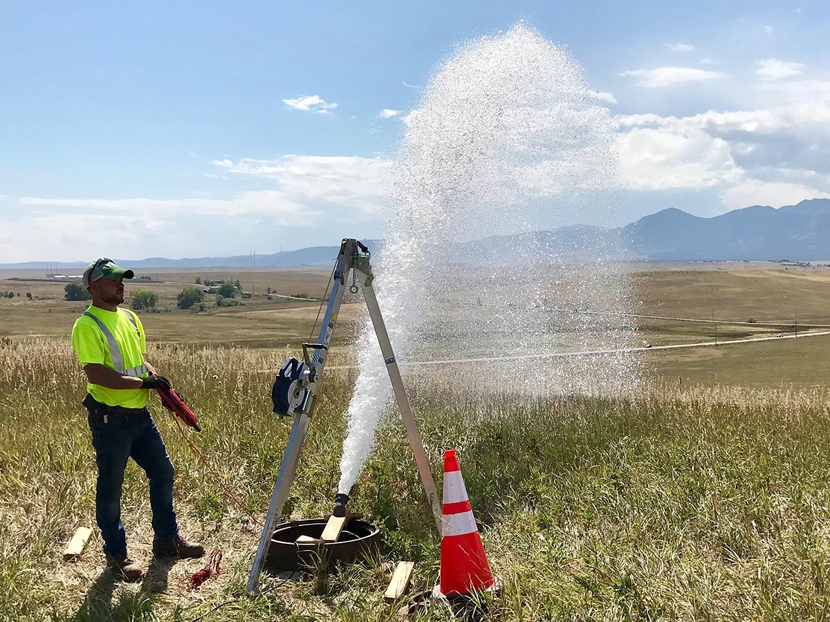 Water is vented from a valve in a field as a HydroMax USA worker looks on.