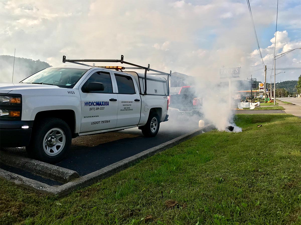 A HydroMax USA Truck next to a smoking manhole during smoke testing.